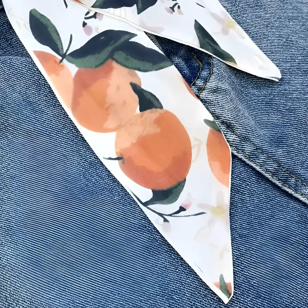 Orange-patterned citrus abstraction scarf belt displayed with Blue Denim Jeans