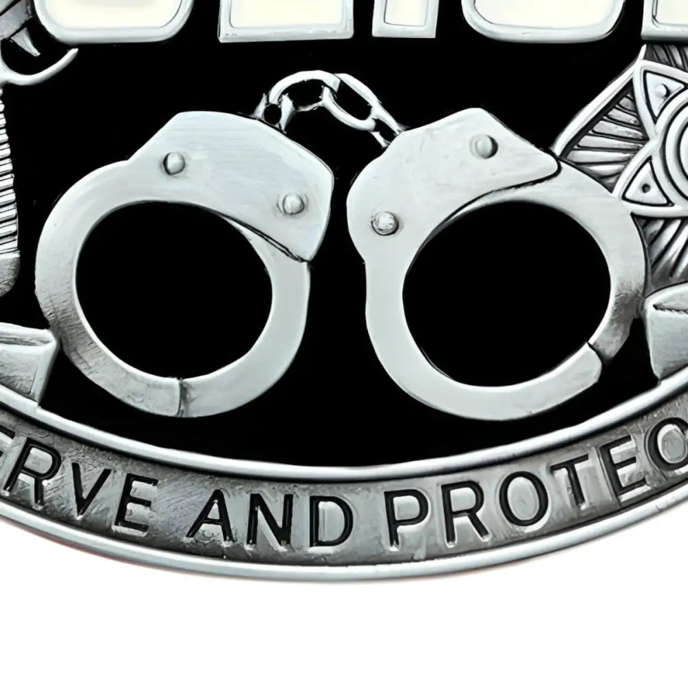 Silver handcuffs on law enforcement belt buckle with badge and gun design
