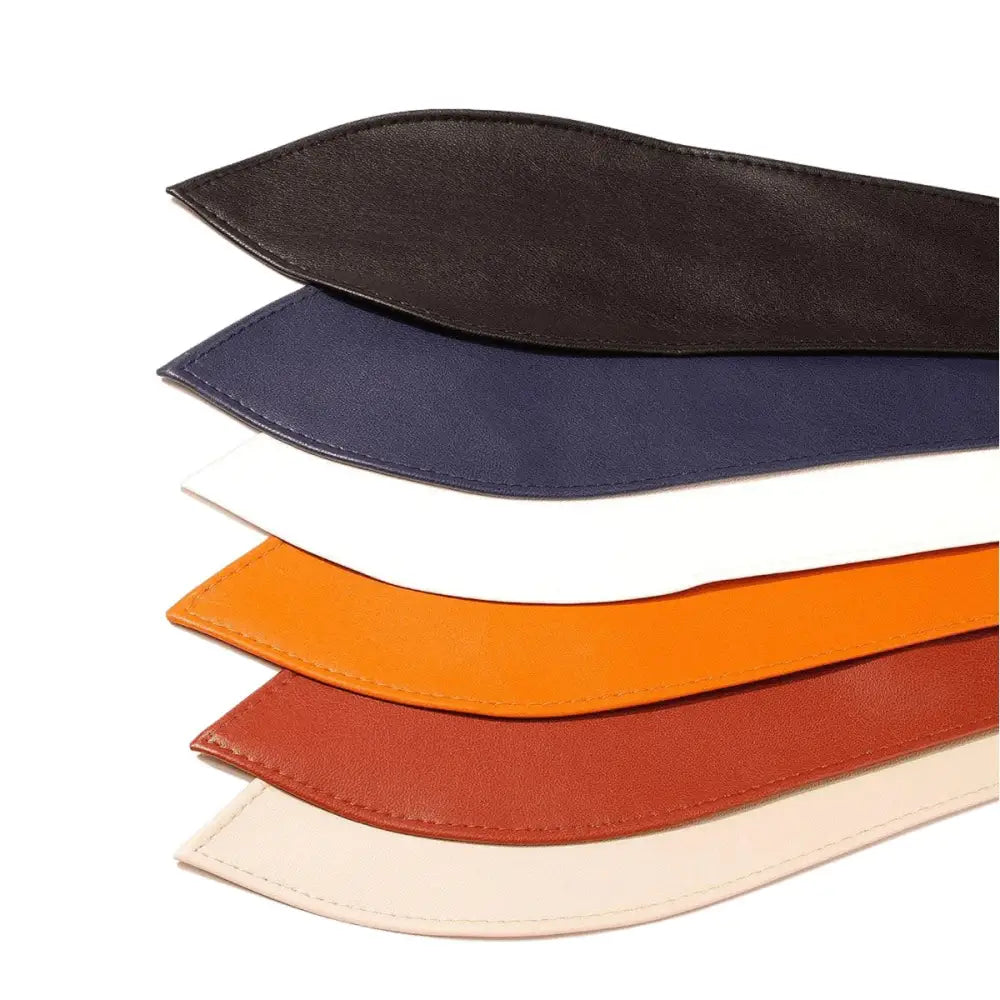 Stacked colorful leather belts showcasing the Elly Belt in brown and black leather for elegant style