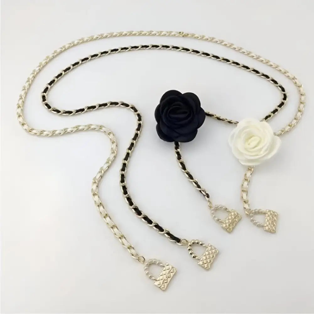 Three black chain belts with white flower accents and decorative charms for women
