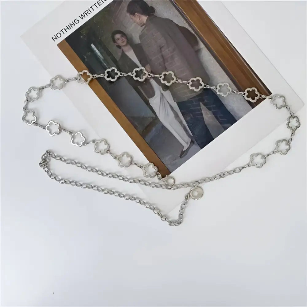 Silver clover chain belt displayed with light blue high-waisted jeans and gold accents