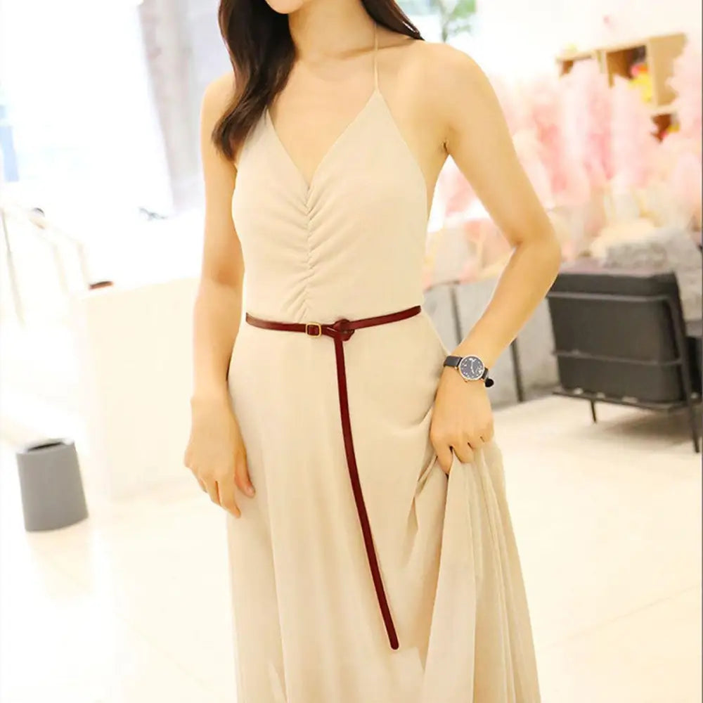 Woman wearing a beige halter dress with a brown belt and gold buckle