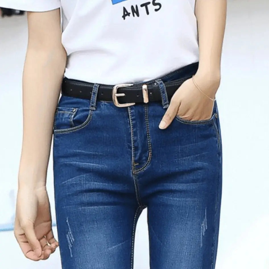 Blue denim jeans with a women’s leather belt featuring a gold buckle accessory