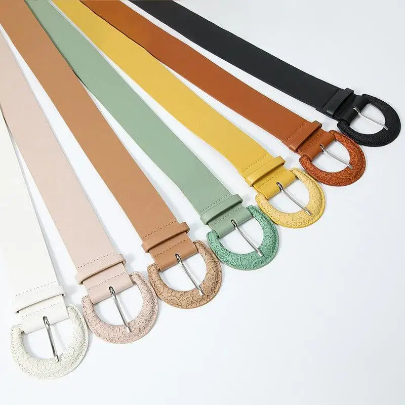 Assorted faux leather belts with decorative textured buckles displayed for fashion accessory product