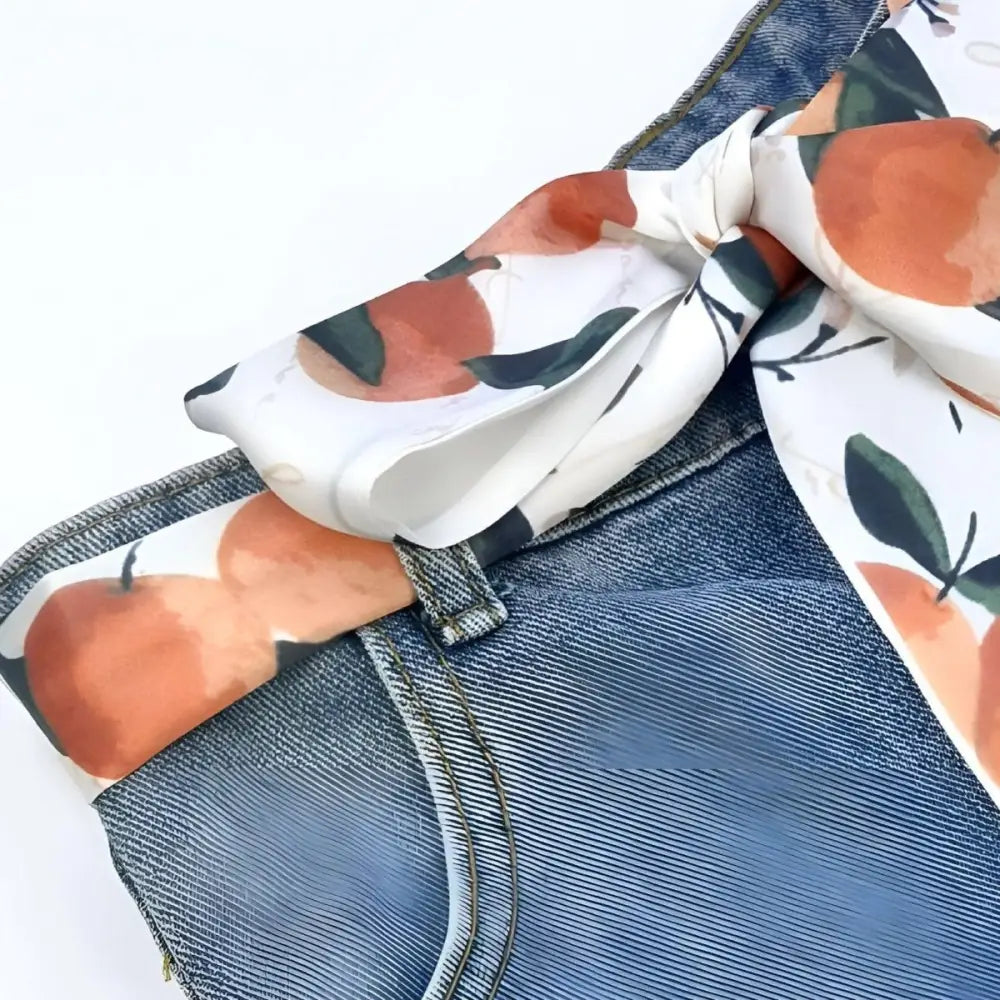 Blue denim jeans with citrus abstraction scarf belt featuring peach pattern and stylish design
