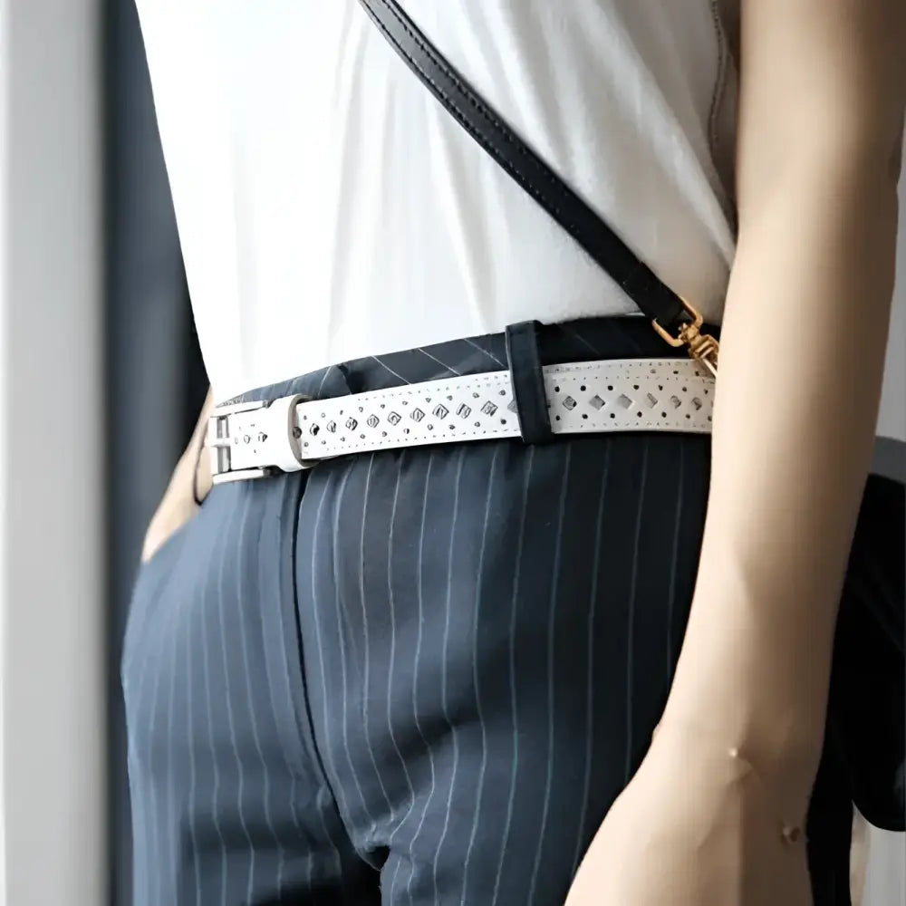 White perforated leather belt displayed with Distressed Denim Shorts featuring diamond cutouts