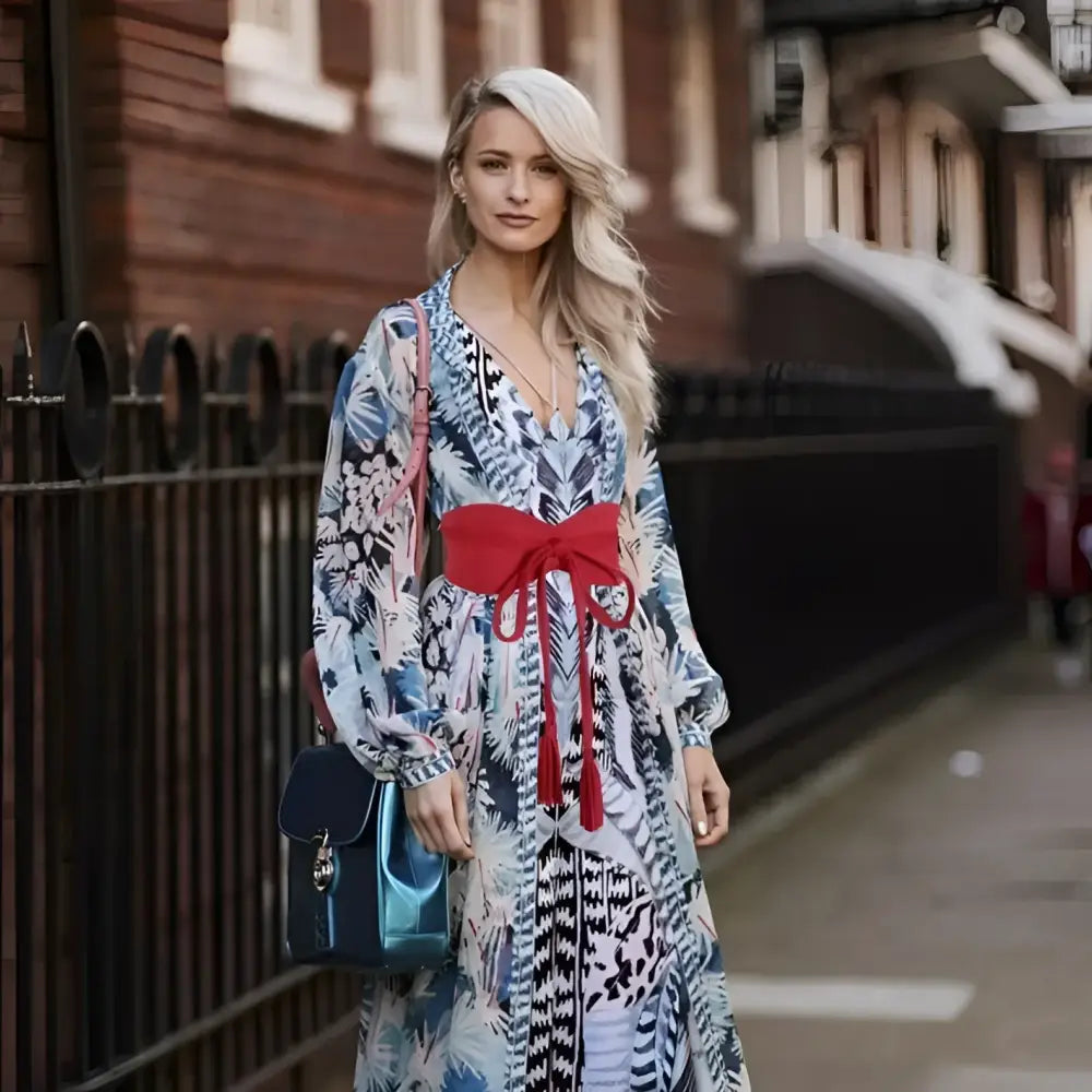 Woman wearing floral print dress with red sash and tassel belt in stylish attire