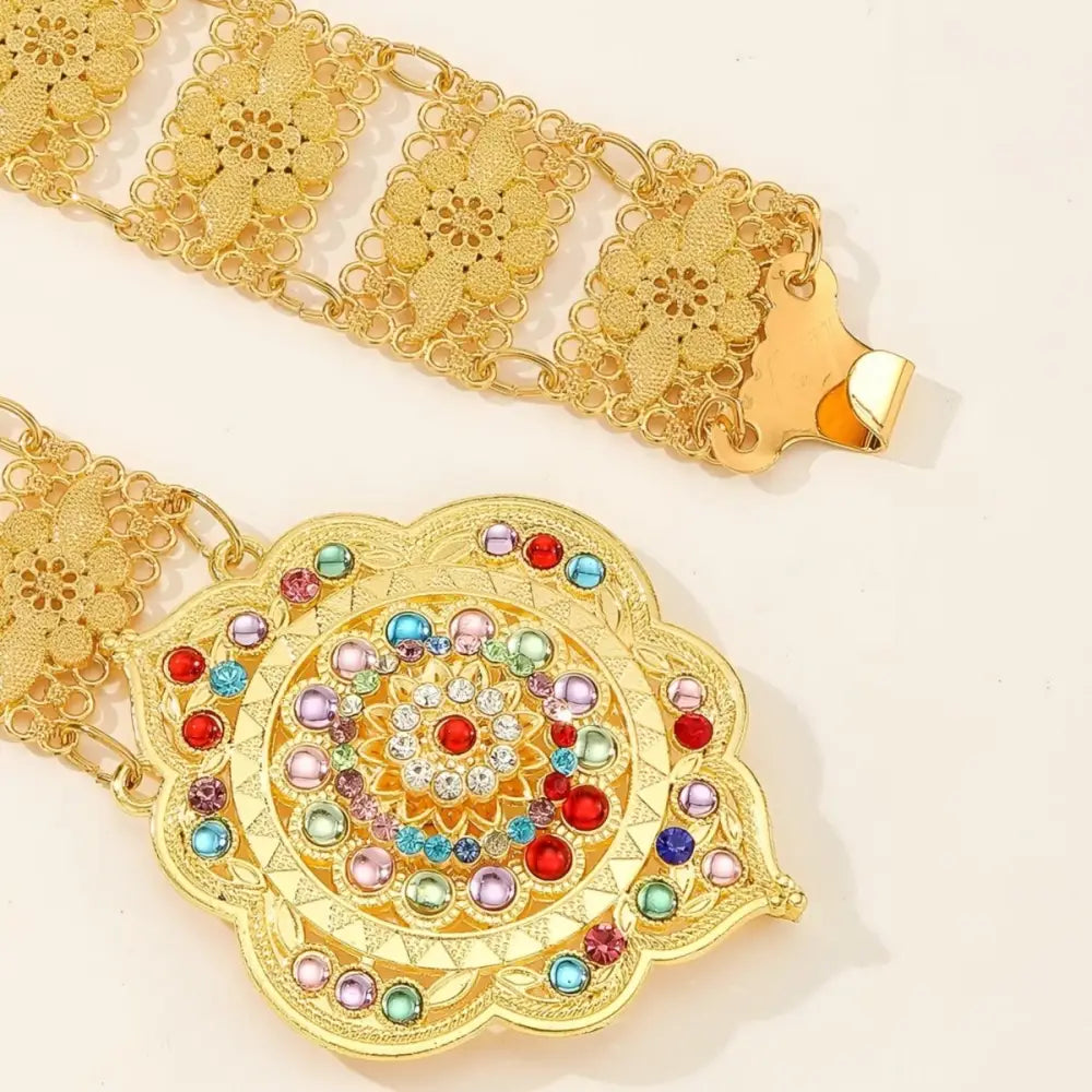 Ornate gold-tone metal belt featuring a jeweled flower buckle and colorful gemstones