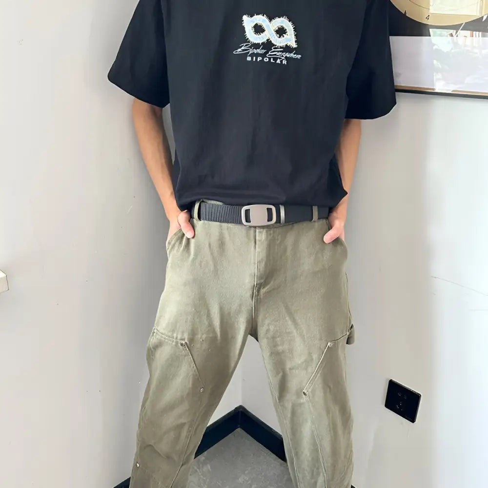 Person wearing black t-shirt and khaki pants showcasing Navy Pleated Shorts with automatic buckle