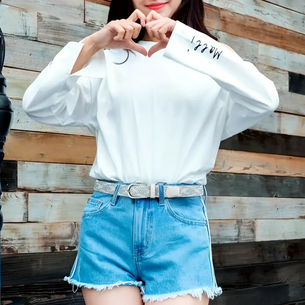 Woman in white blouse and denim shorts with braided elastic belt