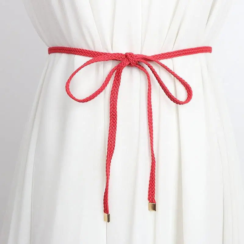White dress featuring a red braided belt with a tie bow for a classic elegant look