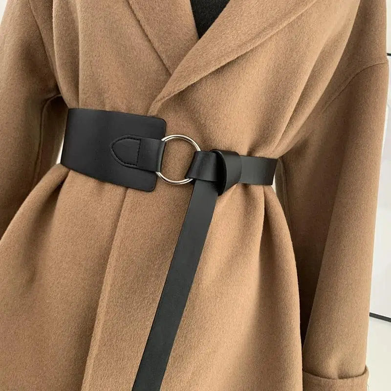 Tan coat featuring a Thanusa Tie Belt with black belt and gold metal ring for stylish formal wear