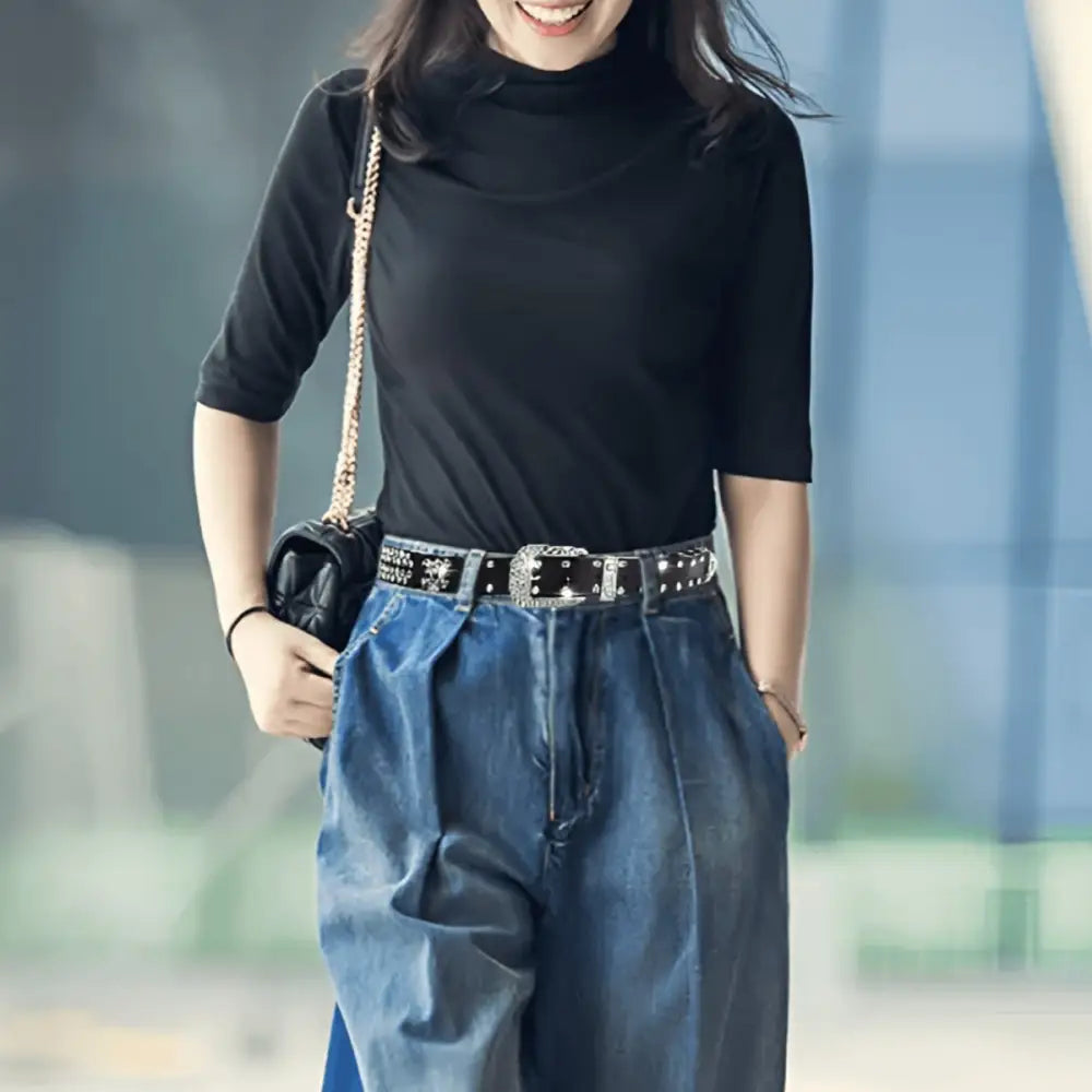 Woman’s outfit featuring black top, wide-leg jeans, and Zephyr rhinestone belt