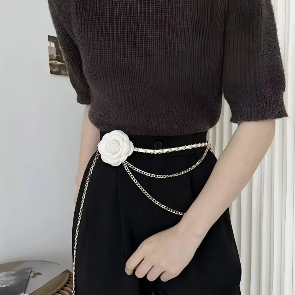 Woman black pants featuring a white flower chain belt with charms for elegant style
