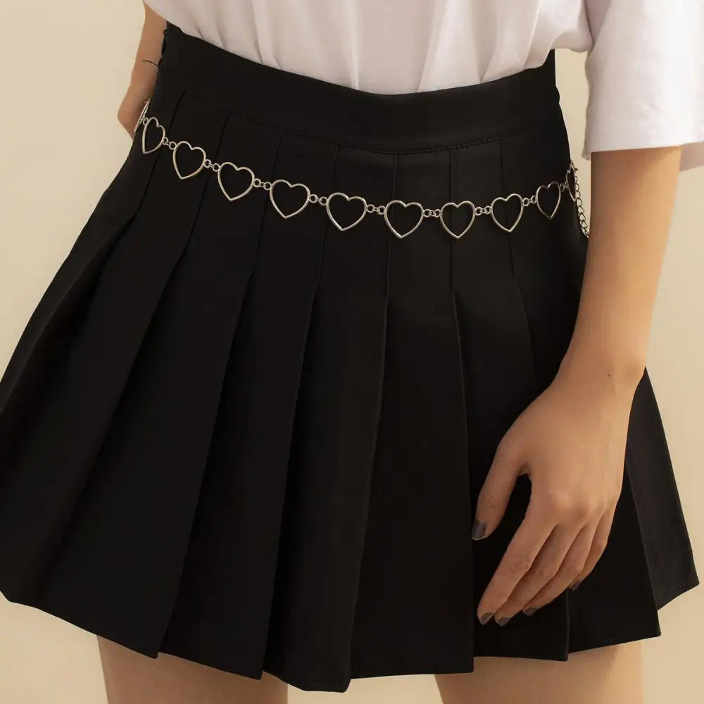 Black pleated skirt with silver and gold-toned chain belt featuring heart details