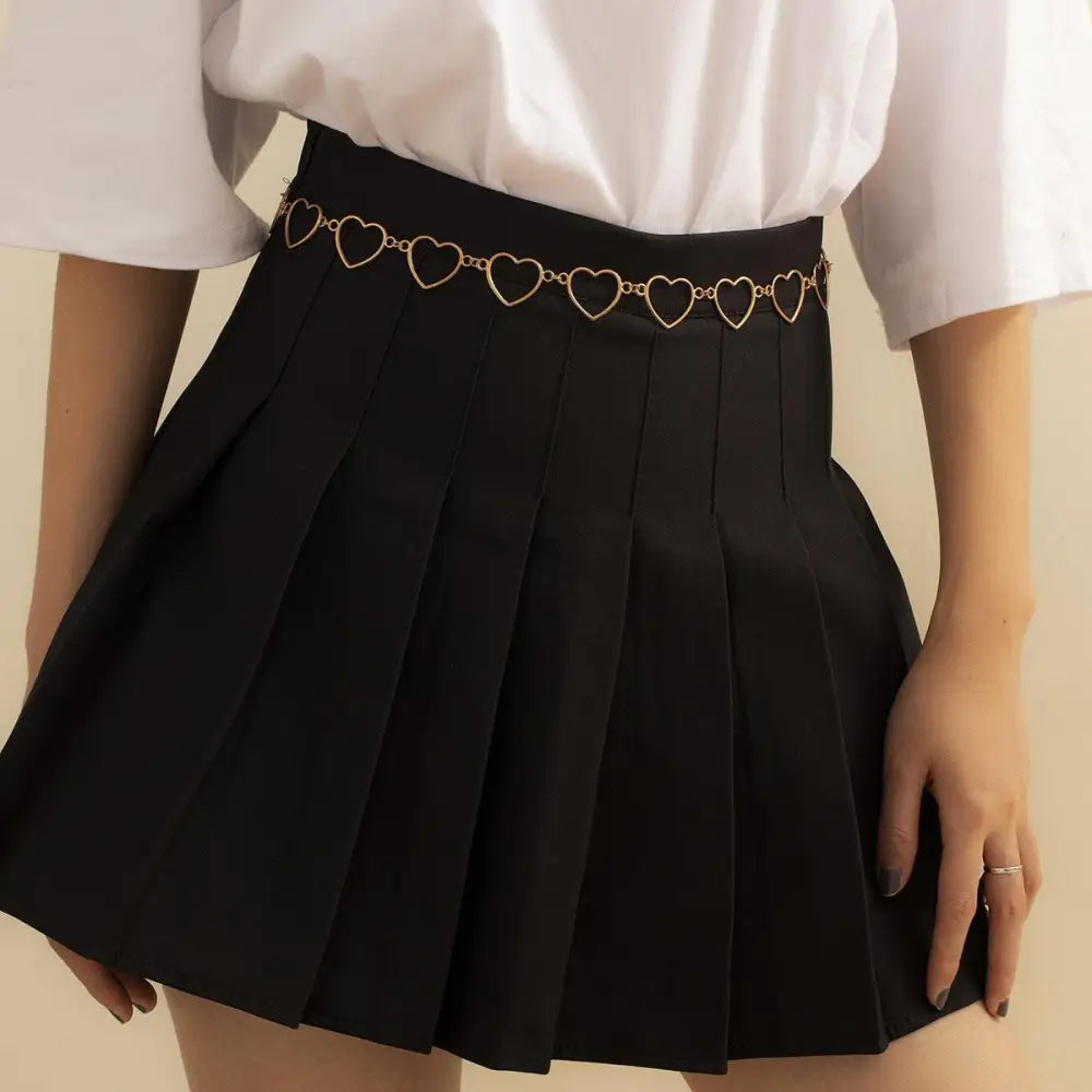 Black pleated skirt with silver and gold-toned chain belt featuring heart details