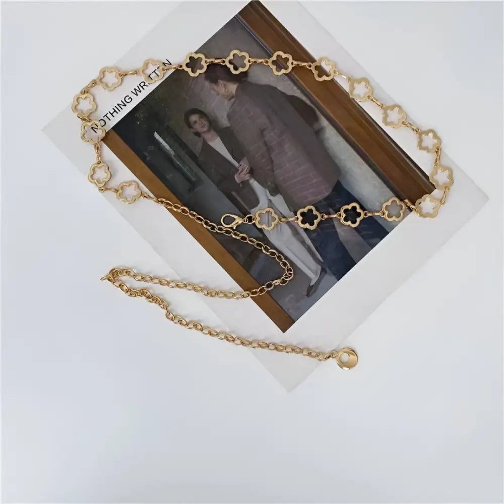 Gold clover chain belt displayed with light blue high-waisted jeans