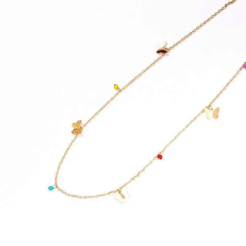 Gold chain necklace with butterfly and bead charms complementing the Black Ribbed Dress with Chain Belt