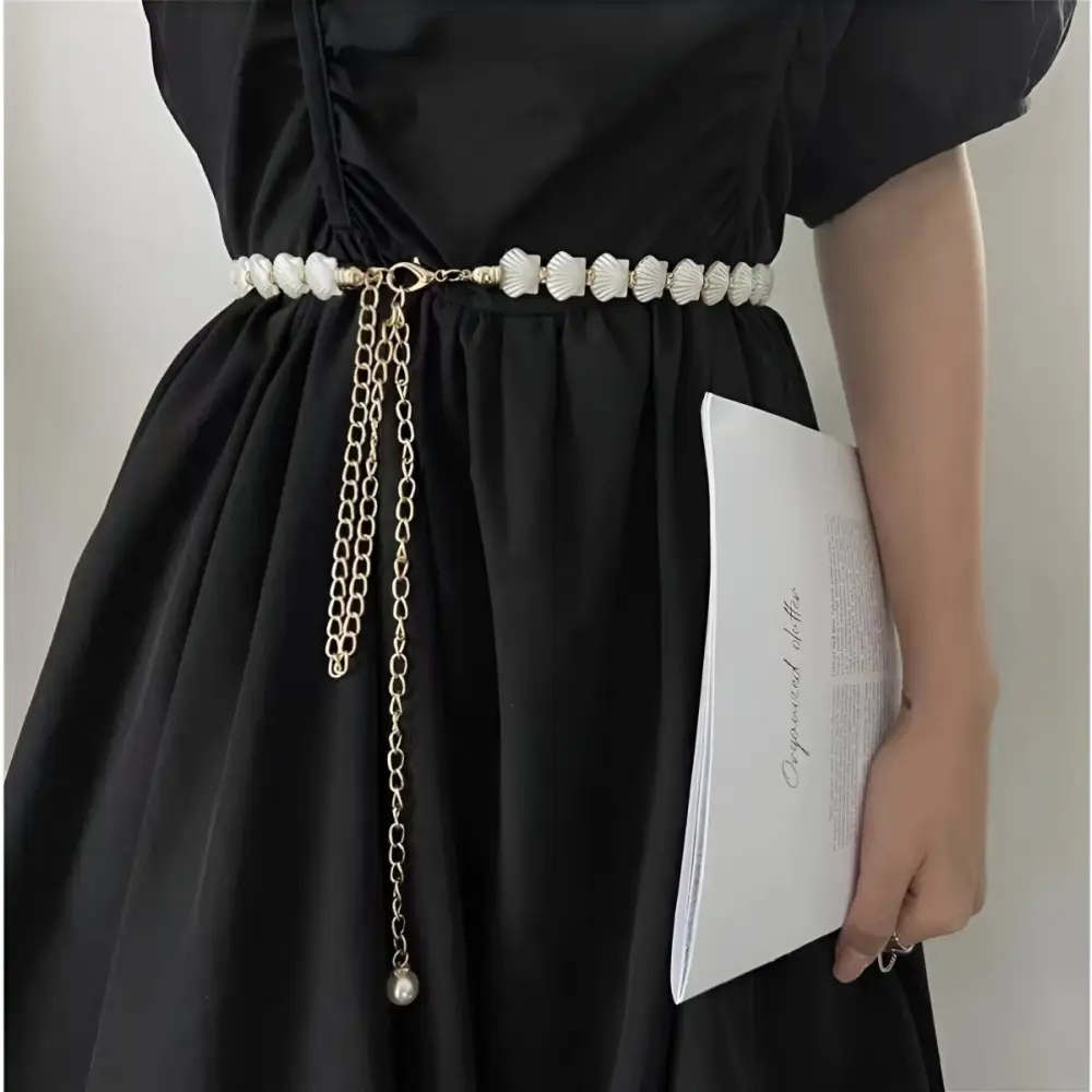 Black dress with Vera Chain belt featuring shell accents and gold chain embellishments