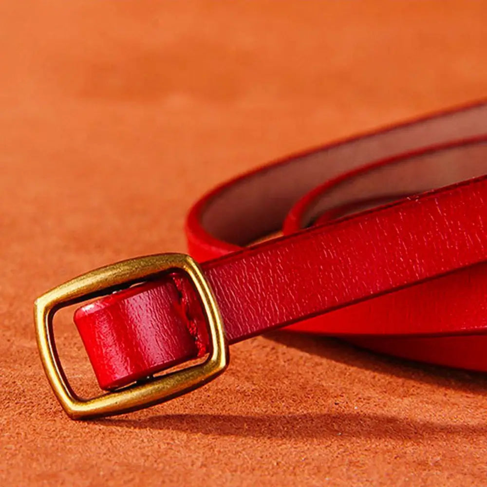 Red leather belt with brass buckle paired with Beige Halter Dress featuring a gold buckle