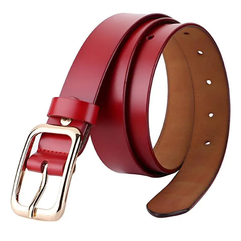 Red leather belt with gold buckle featured in women’s outfit with white sweater and blue jeans