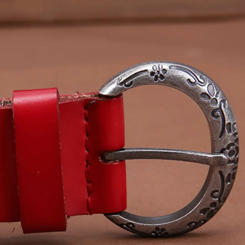 Red leather belt featuring an ornate silver buckle and floral cutout design