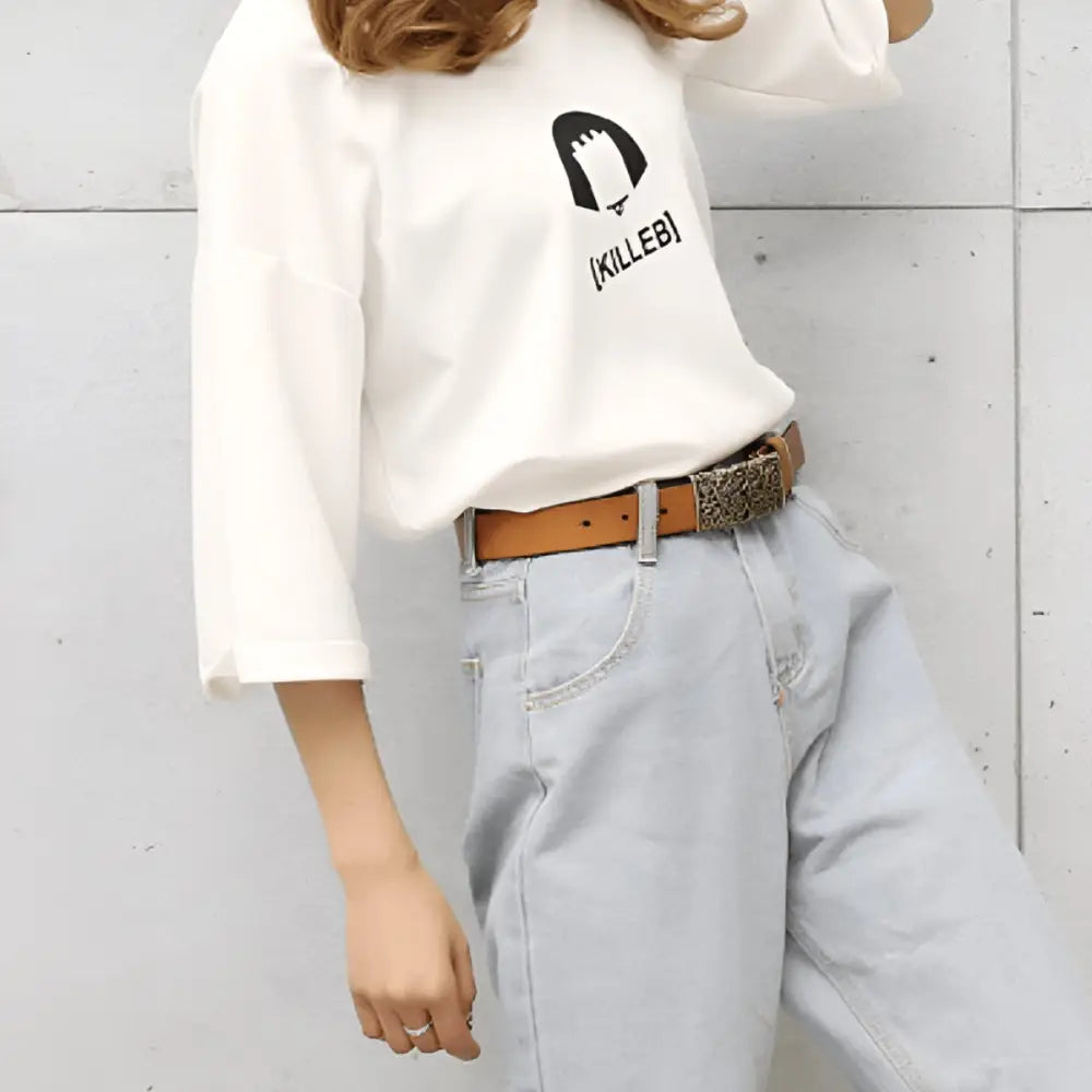 Woman wearing a casual outfit featuring a brown leather belt with an ornate gold buckle