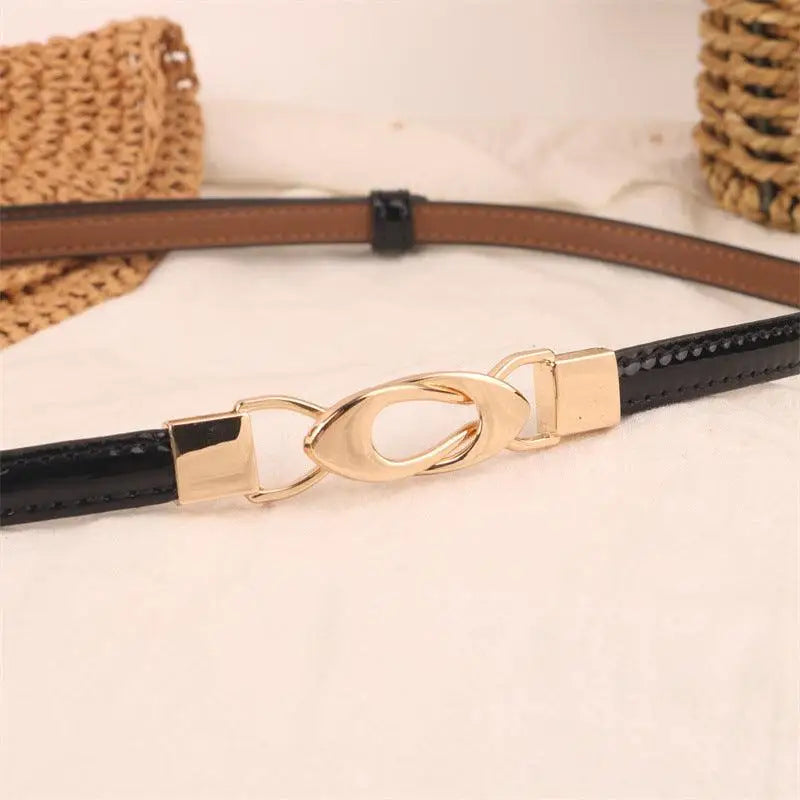 Black patent leather belt featuring a gold decorative buckle for stylish accessorizing