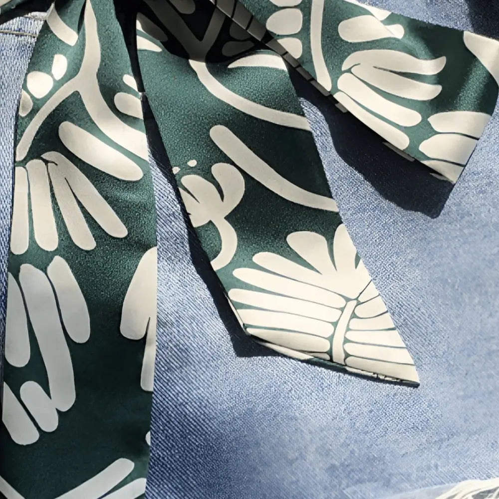 Green and white patterned scarf belt styled with denim shorts for a chic summer look