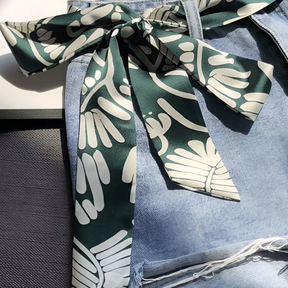 Green and white patterned scarf belt styled with denim shorts for a trendy look