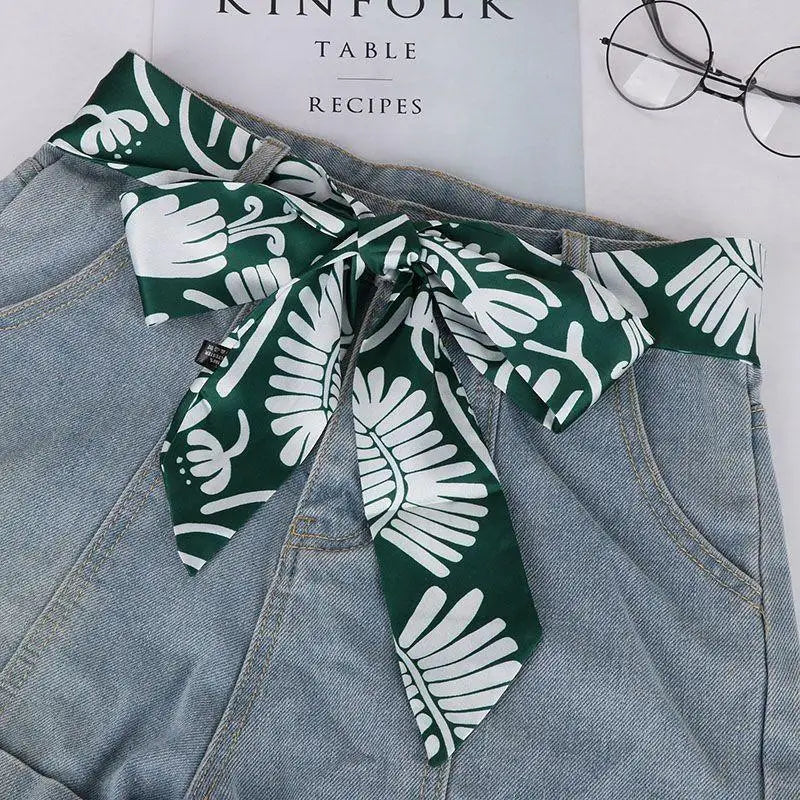 Denim shorts paired with a green floral scarf belt for a stylish summer look
