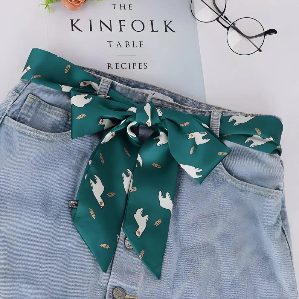 Green scarf tied around jeans with light blue denim skirt and alpaca-patterned scarf belt