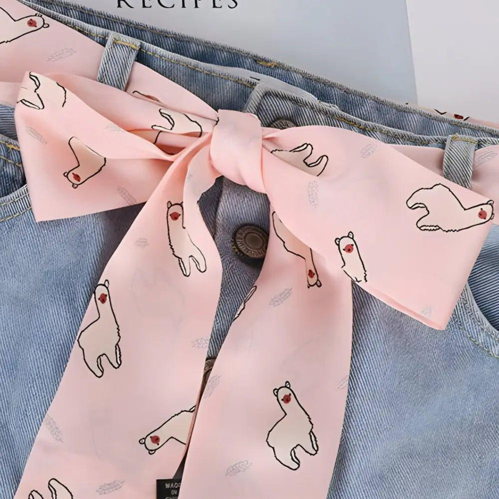Pink alpaca-patterned scarf belt with llama design tied on jeans, South American style