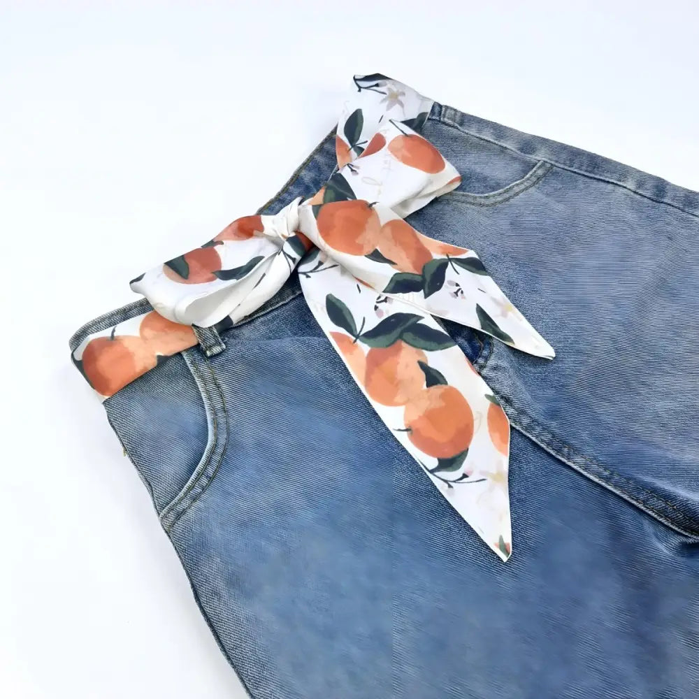 Blue denim jeans with citrus abstraction scarf belt and orange-patterned scarf display