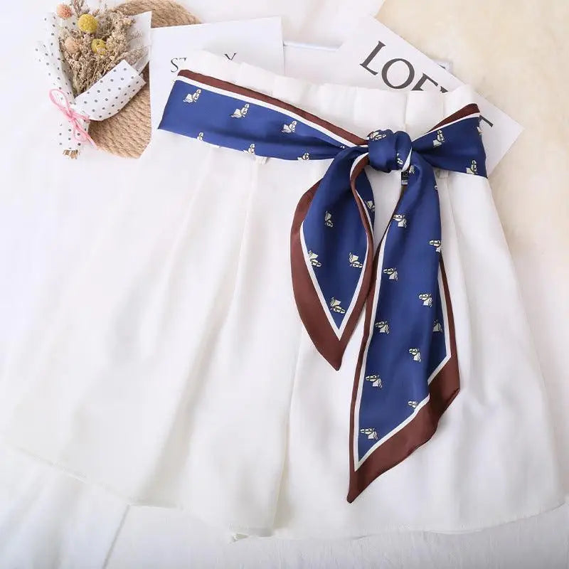 Elegant white shorts with blue patterned silk scarf belt for a stylish look