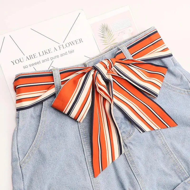 Denim shorts paired with a stylish striped silk scarf belt featuring a bow
