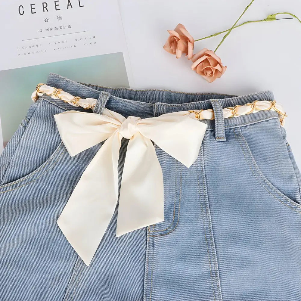 Light blue denim skirt with cream bow belt paired with an Oriana silk scarf for a chic look