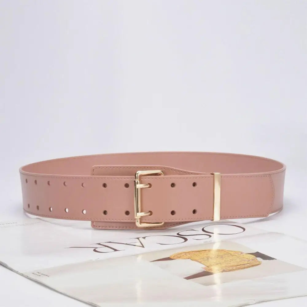 Pink patent leather belt with gold buckle displayed with beige turtleneck sweater and accessories