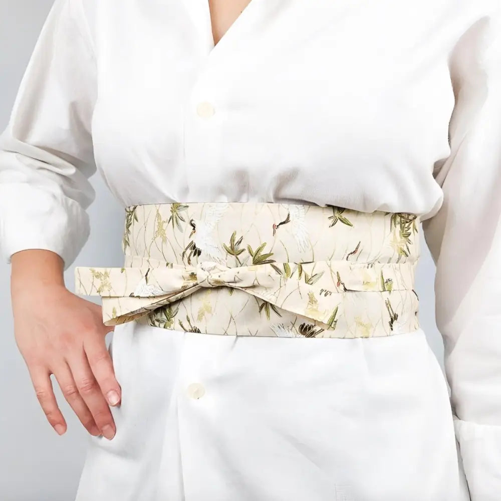 Cream crane patterned fabric featuring an elegant floral-patterned obi belt for traditional attire