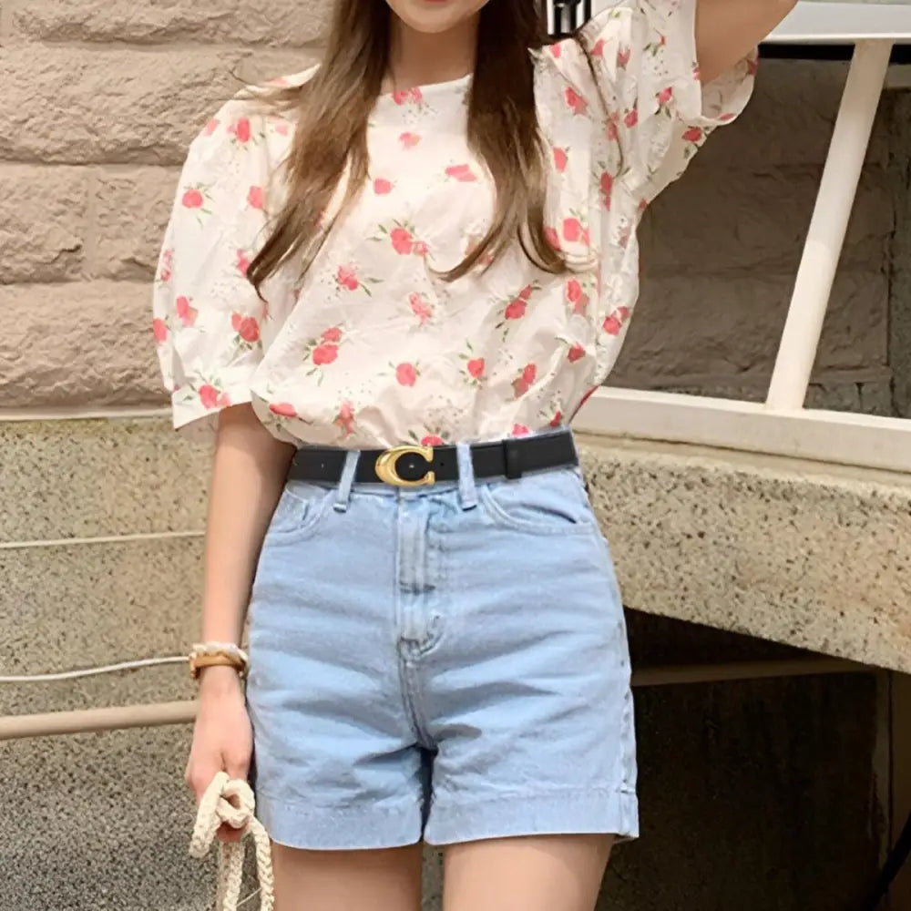 Faux leather belt with gold C-shaped buckle paired with floral blouse and denim shorts
