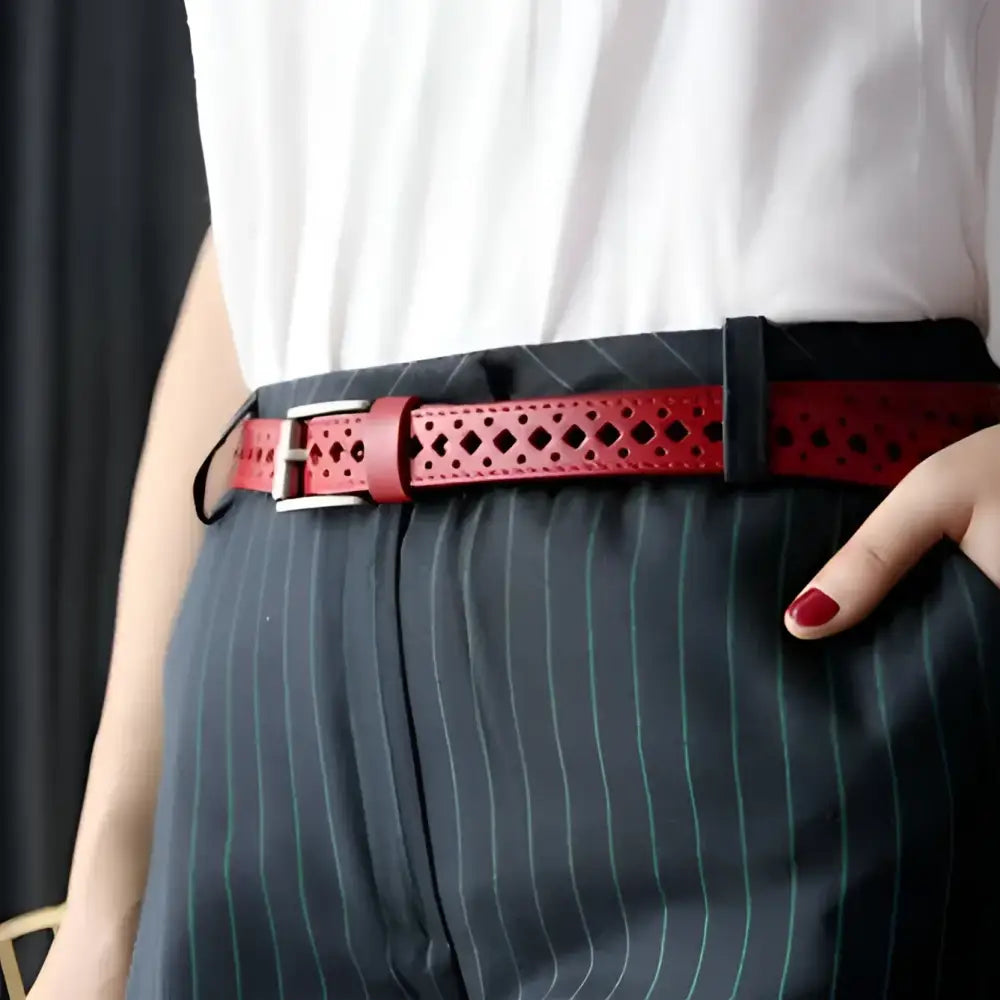 Red leather belt with diamond cutouts displayed with distressed denim shorts