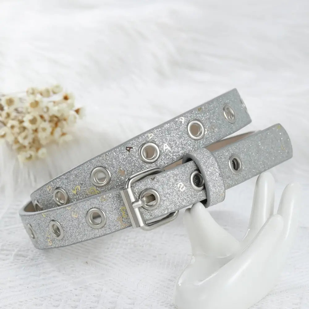 Silver glitter belt with grommet details and a silver buckle for stylish fashion accessorizing