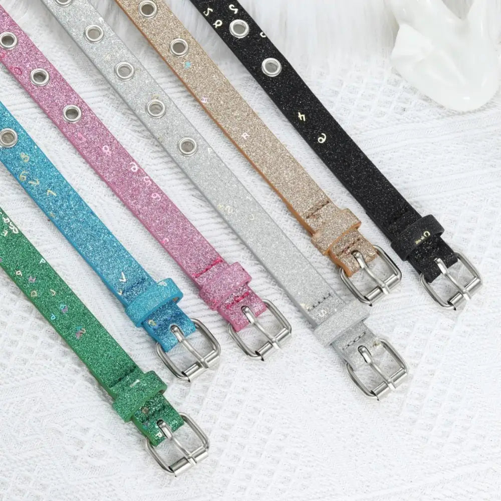 Colorful glittery belts with silver buckles and grommet details displayed for fashion accessory