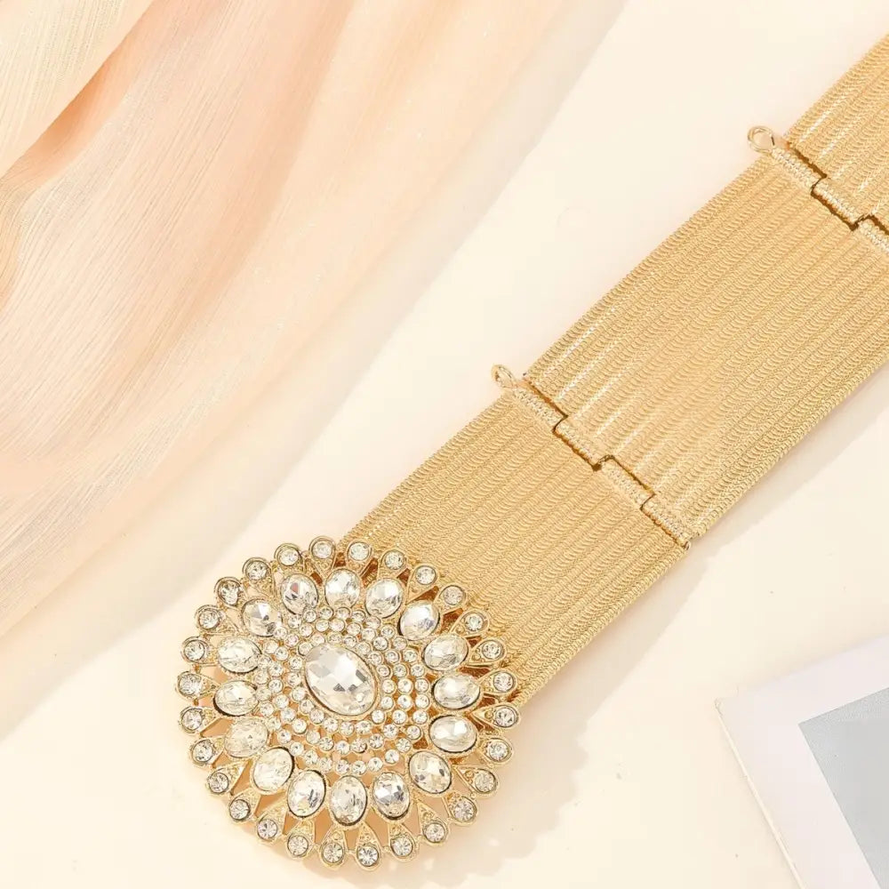 Gold-tone woven belt featuring a jeweled circular buckle for elegant accessory style