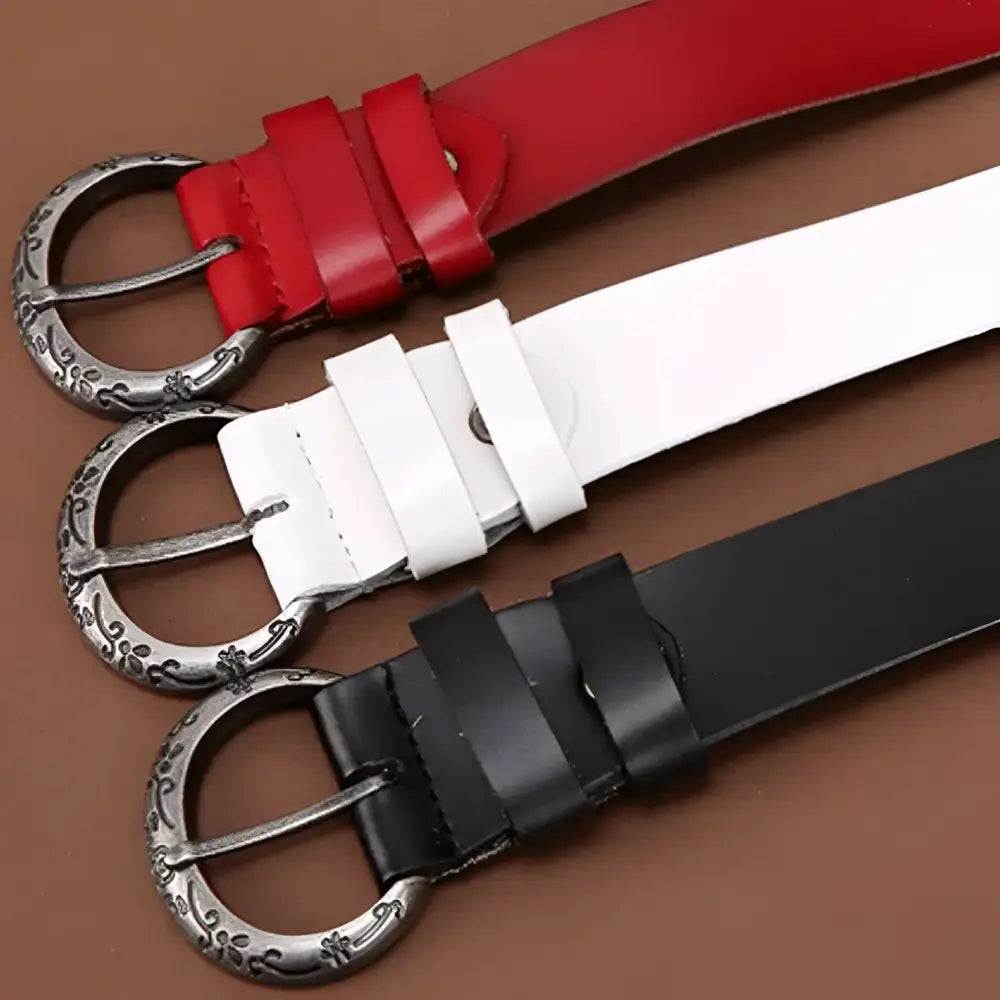 Three leather belts with decorative buckles and floral cutouts displayed as product