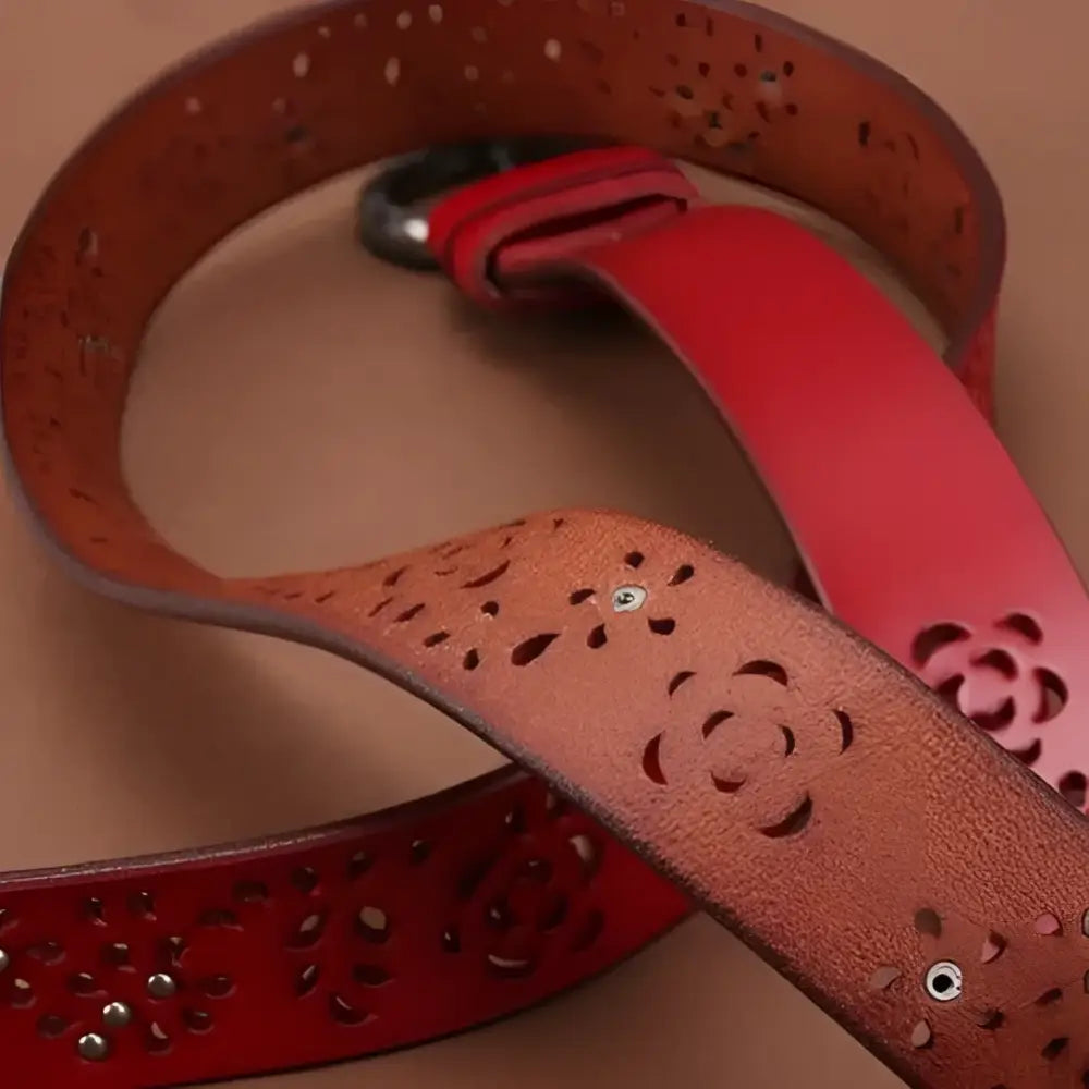 Two leather belts with floral cutouts and decorative buckles on display