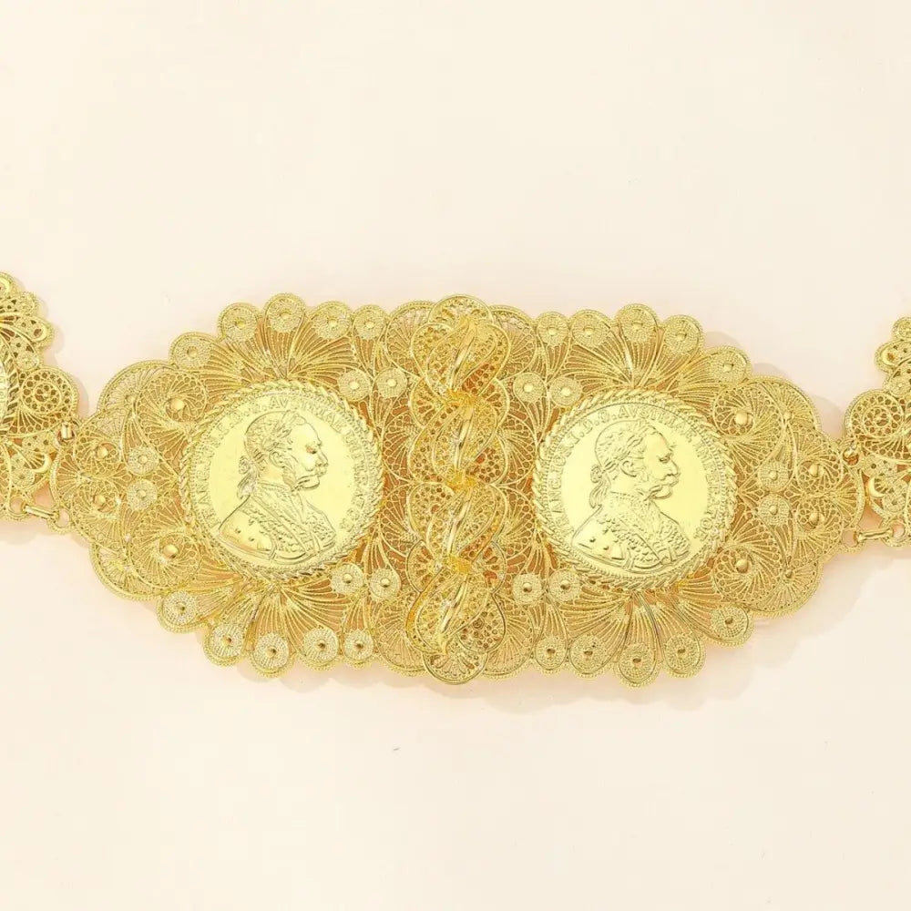 Elegant ornate gold coin belt displayed on patterned blue fabric for luxurious fashion