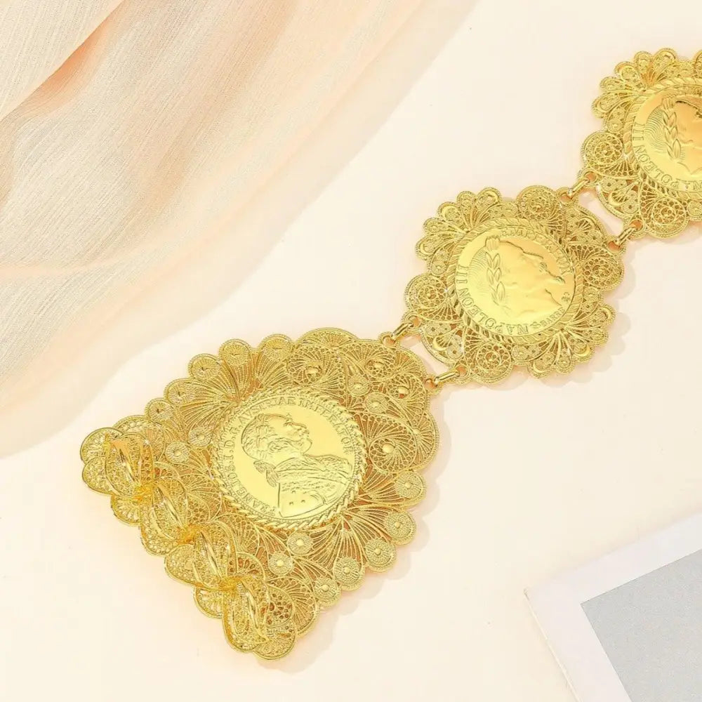Ornate gold coin belt displayed on patterned blue fabric in a product image