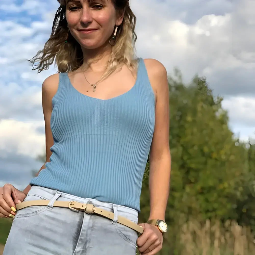 Woman wearing a blue ribbed tank top showcasing the Roxane Leather Belt and leather accessories
