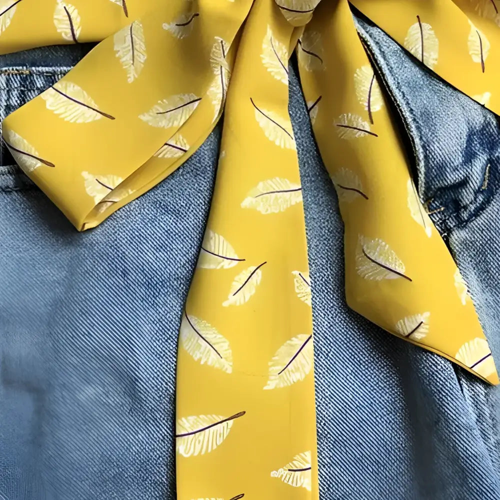 Yellow feather-patterned Ipadia scarf belt tied to denim shorts for stylish accessories